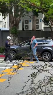 男子斑马线旁与警察争吵，转身走向灰色汽车又回头对峙，上车后警察追到车窗继续谈